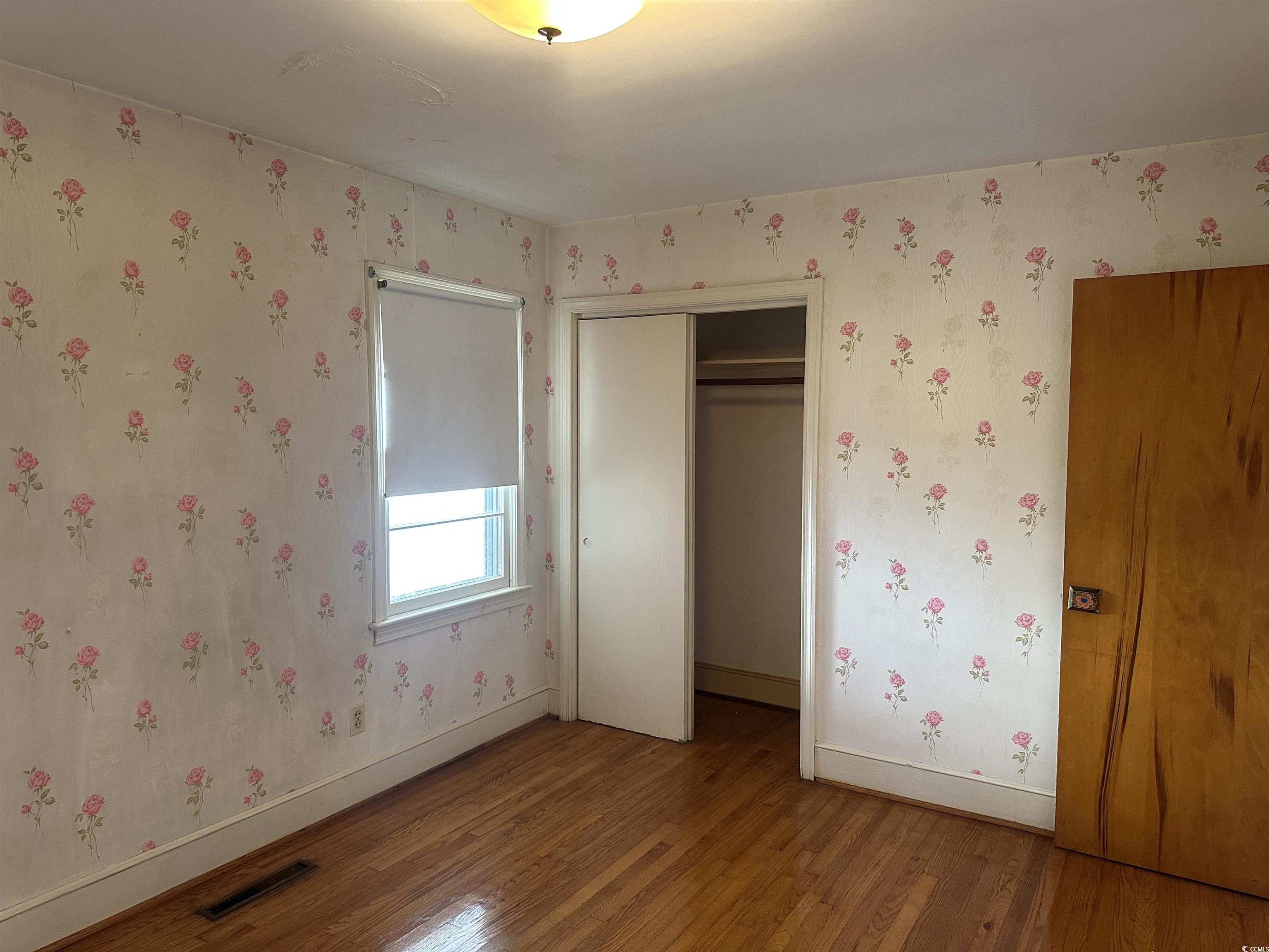 103 East 2nd Avenue Lake View, SC 29563 - Photo 12 of 16 Unfurnished bedroom featuring wood finished floors, a closet, and wallpapered walls
