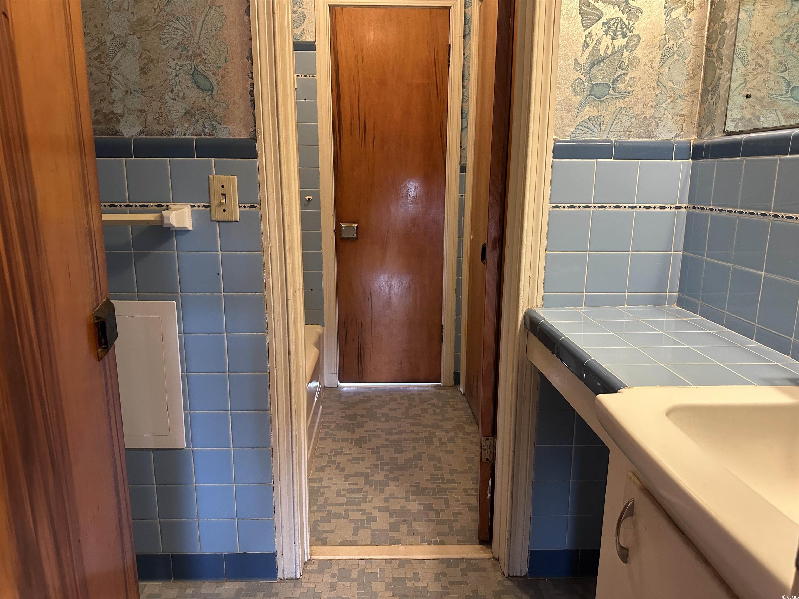 103 East 2nd Avenue Lake View, SC 29563 - Photo 15 of 16 Full bathroom featuring wallpapered walls, tile walls, a wainscoted wall, a bathtub, and vanity