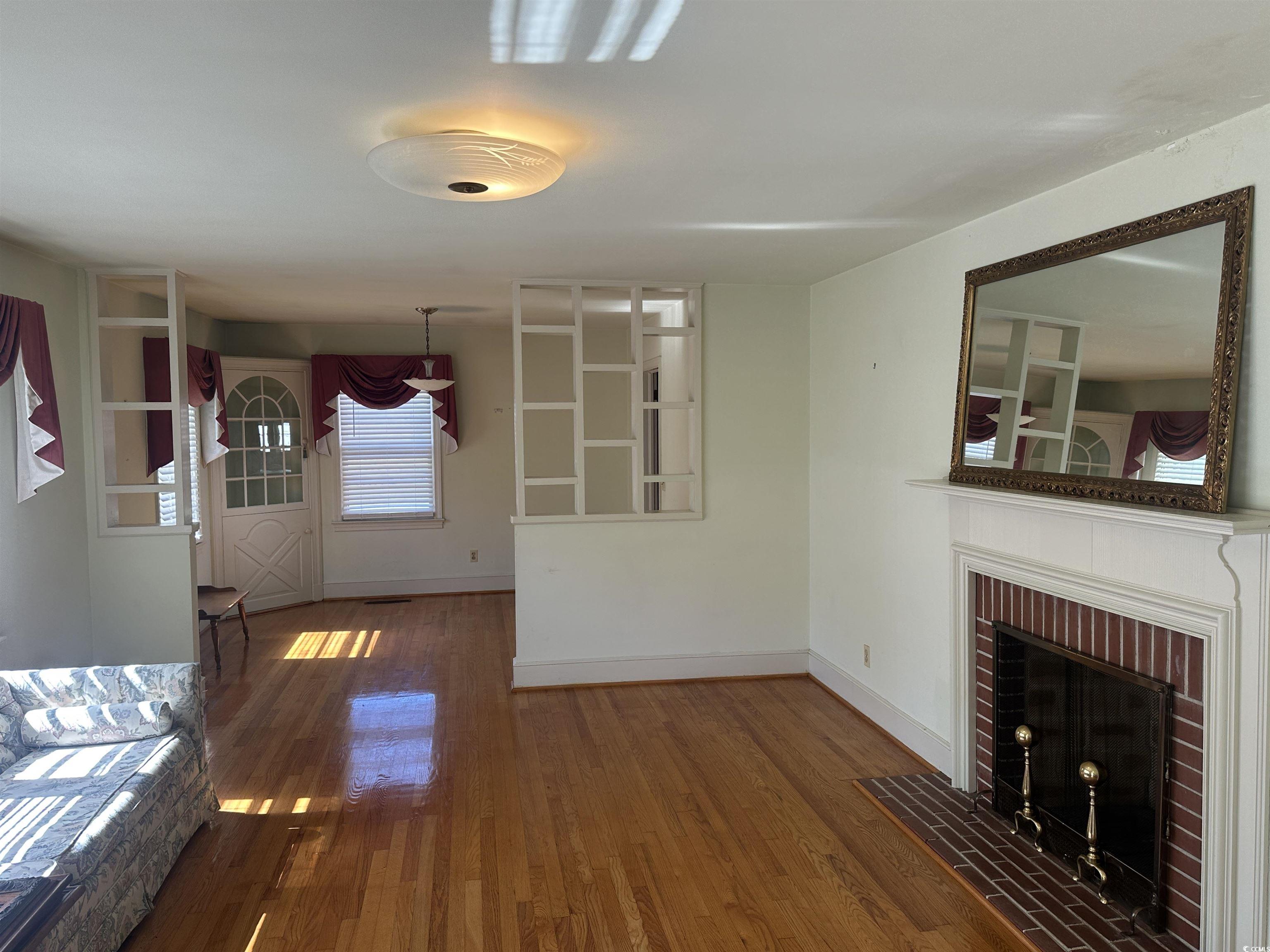 103 East 2nd Avenue Lake View, SC 29563 - Photo 5 of 16 Unfurnished living room with hardwood / wood-style floors and a fireplace