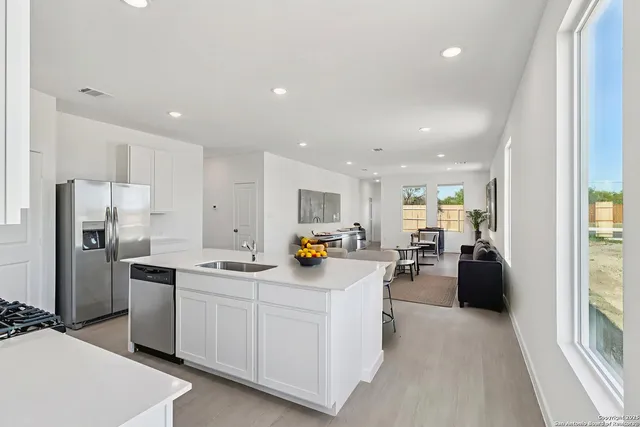 a kitchen with stainless steel appliances a refrigerator a sink a stove and white cabinets next to a window