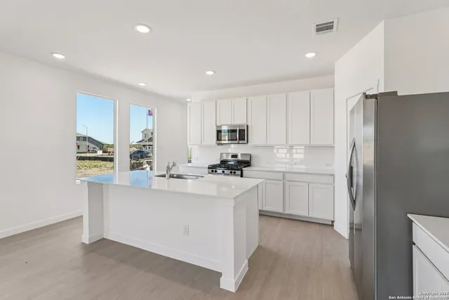 a kitchen with kitchen island white cabinets and refrigerator