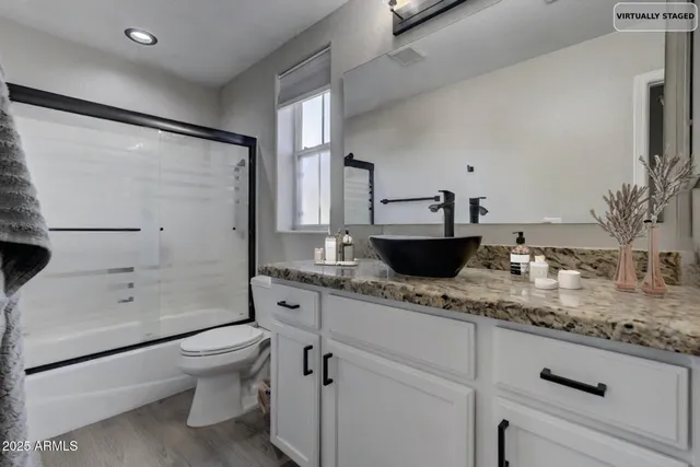a bathroom with a granite countertop sink a toilet and shower