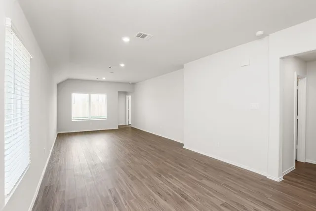 an empty room with wooden floor and windows