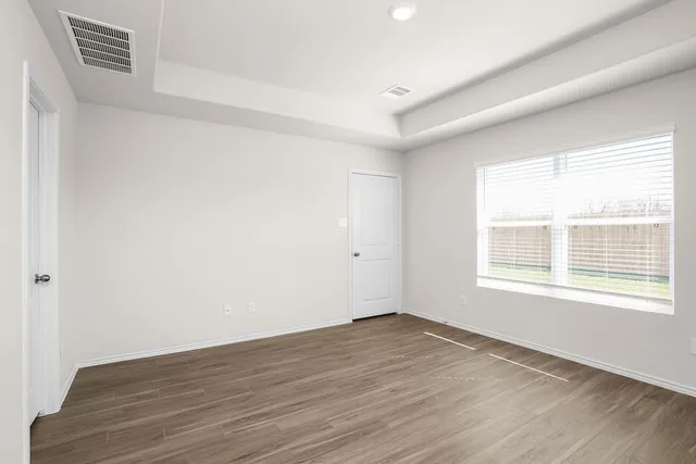 an empty room with wooden floor and windows