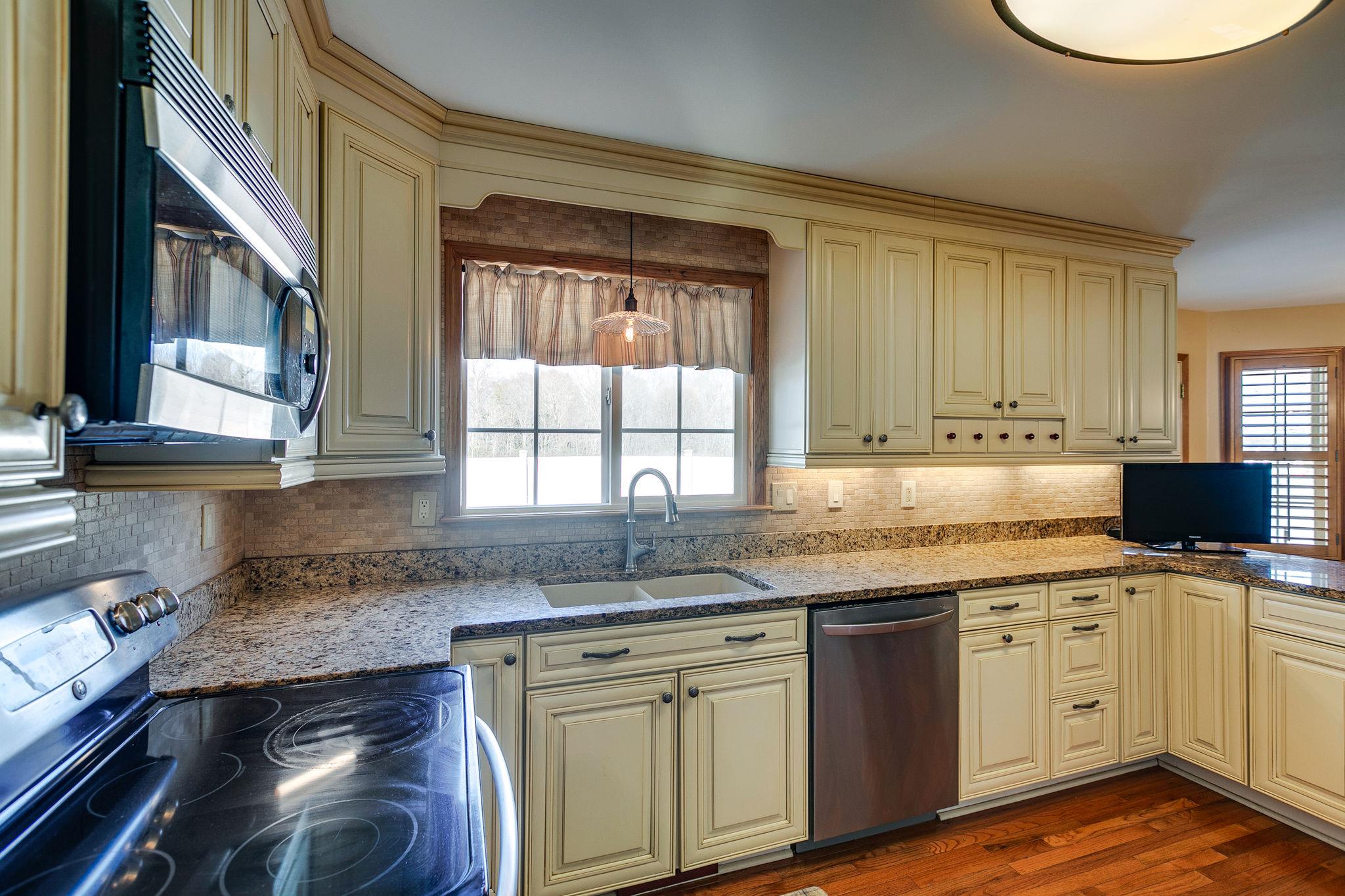 3467 Greens Mill Road Spring Hill, TN 37174 - Photo 16 of 28 a kitchen with granite countertop a sink cabinets a window and stainless steel appliances