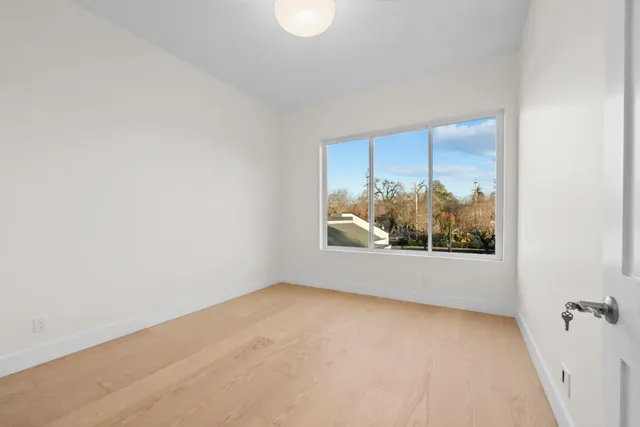 a large white kitchen with granite countertop a stove a sink and a large window