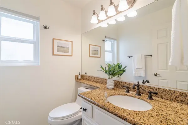 a bathroom with a granite countertop toilet a sink and a mirror