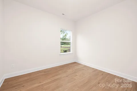 an empty room with wooden floor and window