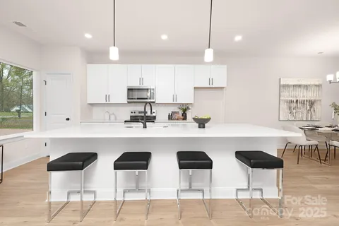 a kitchen with stainless steel appliances a dining table chairs sink and cabinets