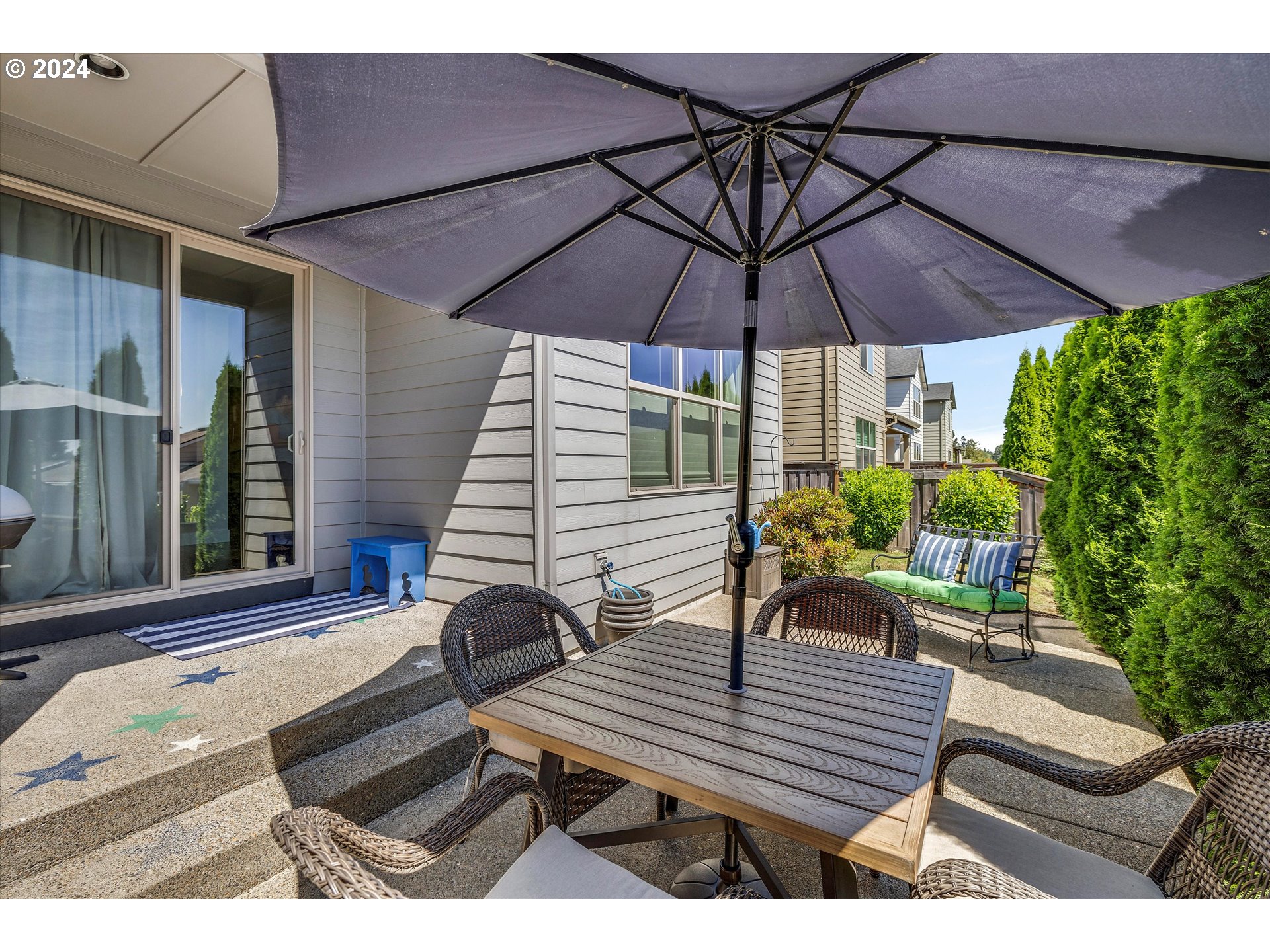 12934 Southwest Buckfield Lane Portland, OR 97224 - Photo 23 of 27 a view of a patio with a dining table and chairs under an umbrella