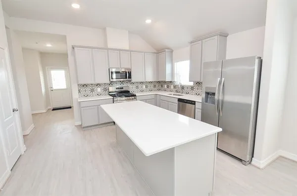 a large white kitchen with a refrigerator a stove a sink and a window