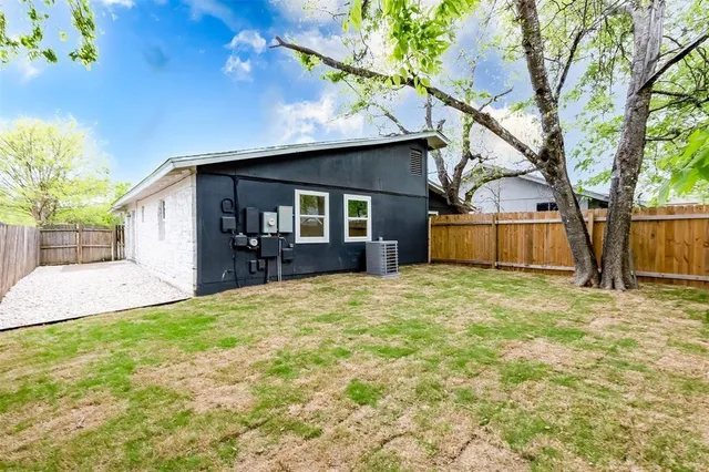 a view of a house with a large tree and wooden fence