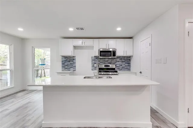 a kitchen with stainless steel appliances a microwave a sink and a refrigerator