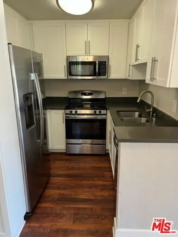 a kitchen with stainless steel appliances a refrigerator a stove and a sink with wooden floor