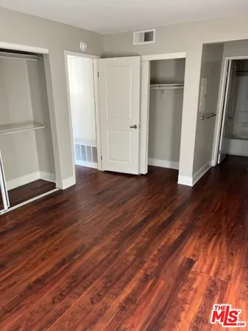 an empty room with wooden floor and entrance