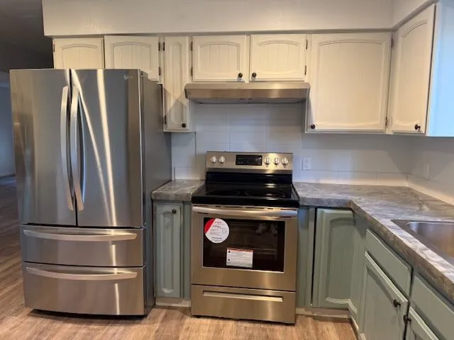 a kitchen with stainless steel appliances granite countertop a stove a sink and a refrigerator