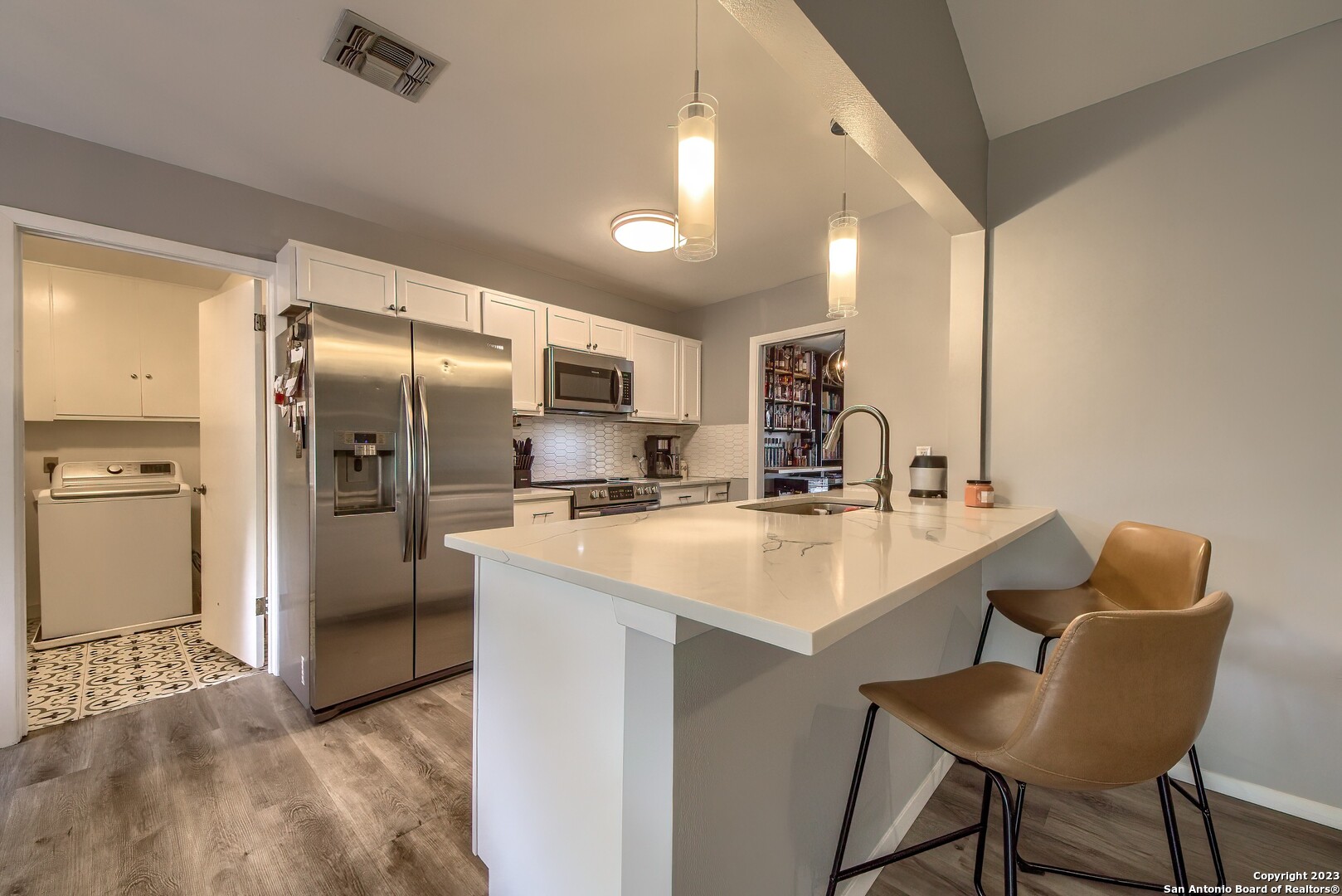 a kitchen with refrigerator and chairs