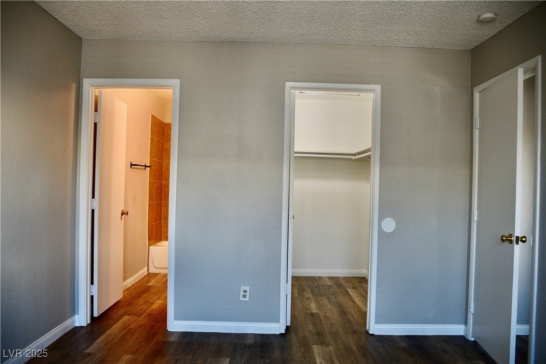 6925 Hopkins Drive, Unit 3 Las Vegas, NV 89156 - Photo 8 of 12 Unfurnished bedroom with dark wood-style floors, a textured ceiling, and a spacious closet