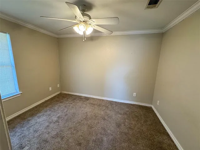 an empty room with a chandelier fan and wooden floor