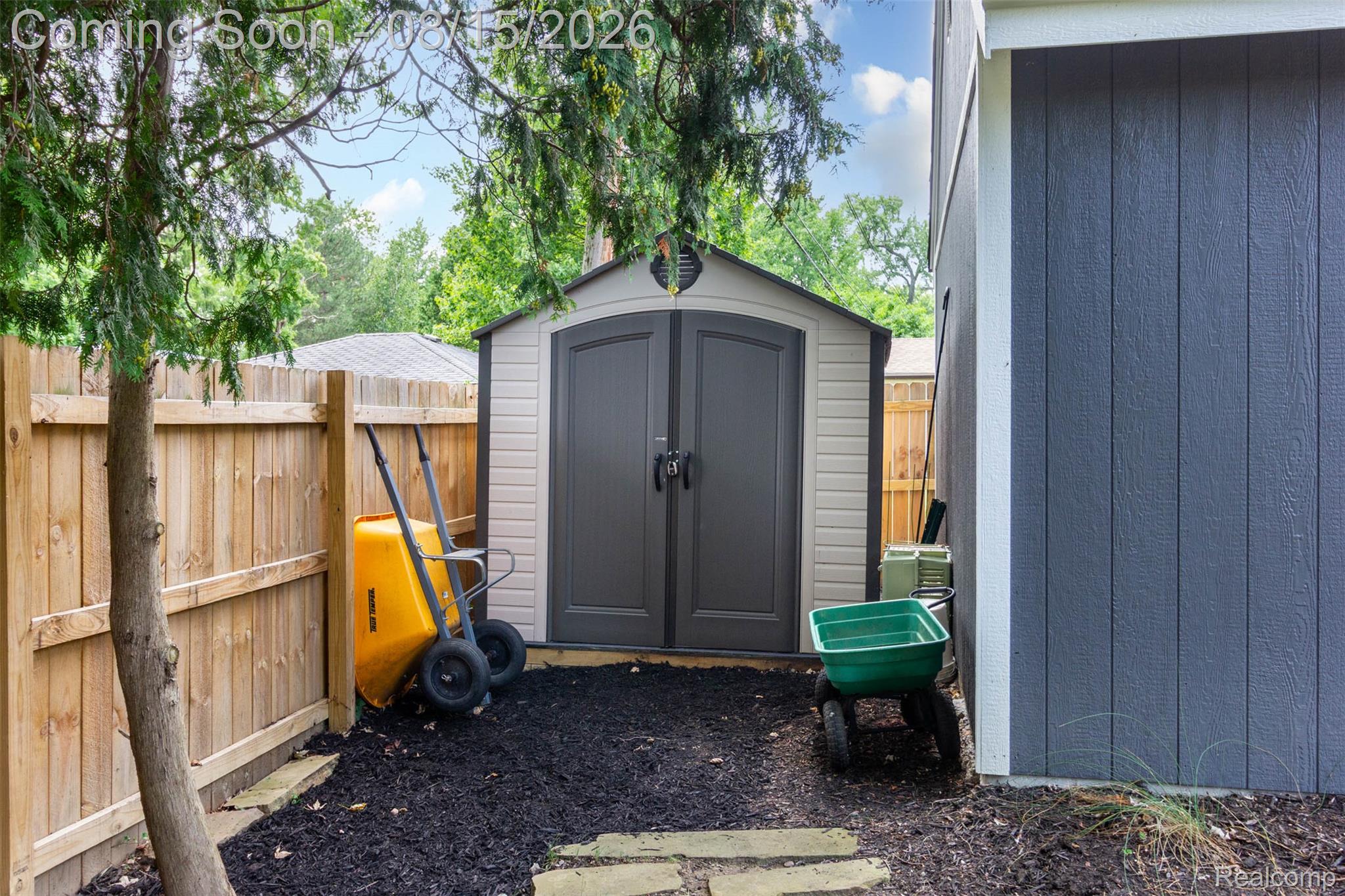 29604 Chelmsford Road Southfield, MI 48076 - Photo 36 of 39 Outdoor storage shed with dual gray doors, wood privacy fencing, and dark ground cover