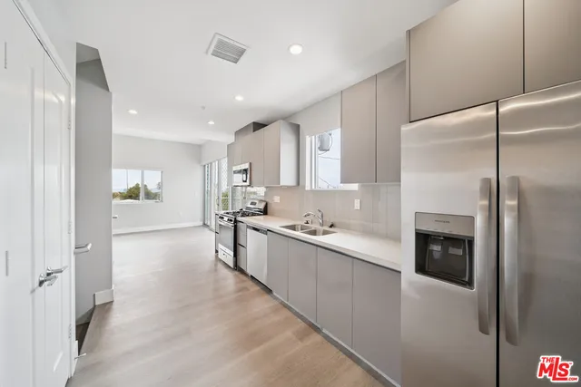 a kitchen with stainless steel appliances kitchen island granite countertop a refrigerator and a sink