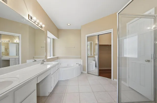 a spacious bathroom with a bathtub shower sink mirror and toilet