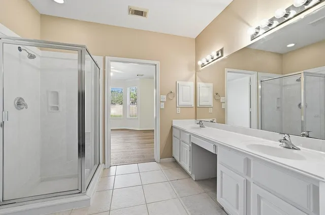a bathroom with a double vanity sink a large mirror and shower