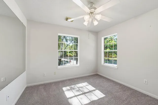 an empty room with windows and fan