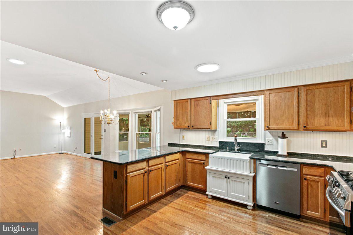 8307 Southstream Run Springfield, VA 22153 - Photo 25 of 49 a kitchen with granite countertop a stove a sink dishwasher and white cabinets with wooden floor