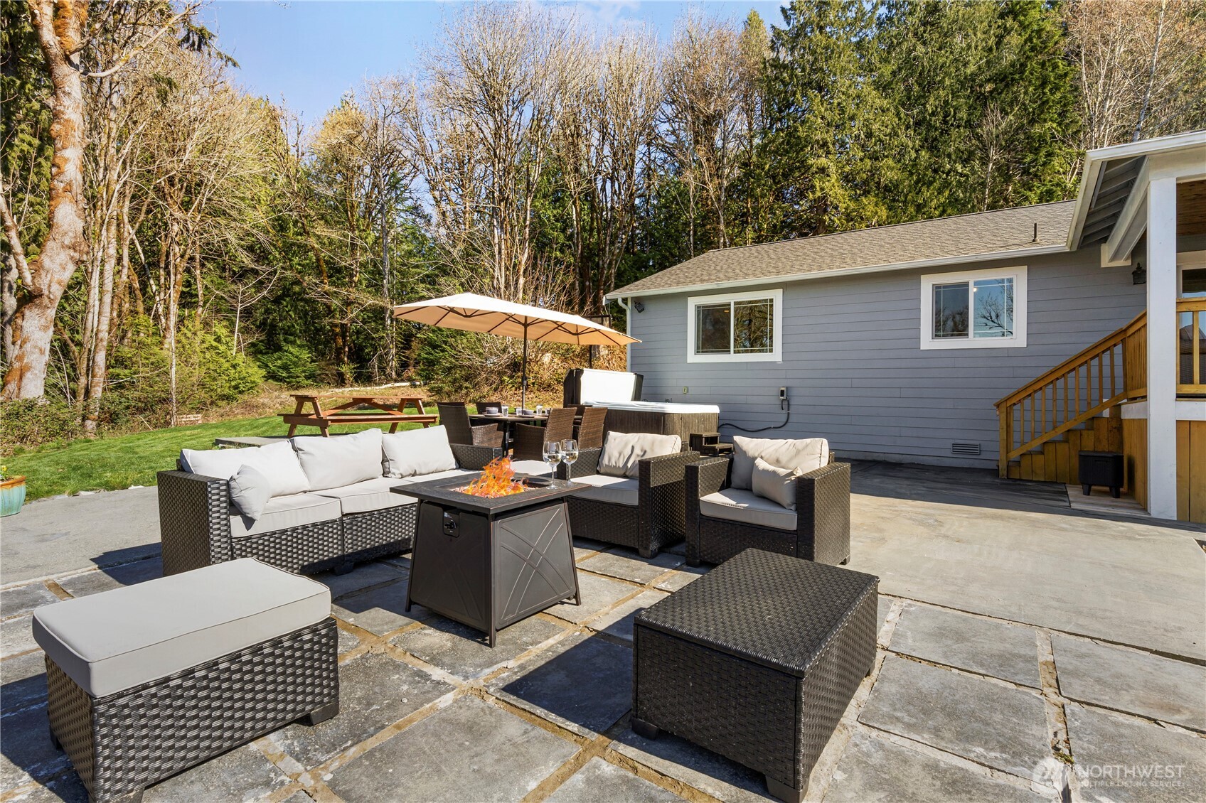 31 East Cove View Drive Belfair, WA 98528 - Photo 18 of 23 a view of a patio with couches table and chairs under an umbrella with large trees