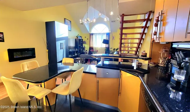 a kitchen with stainless steel appliances kitchen island granite countertop a table chairs in it and wooden floors