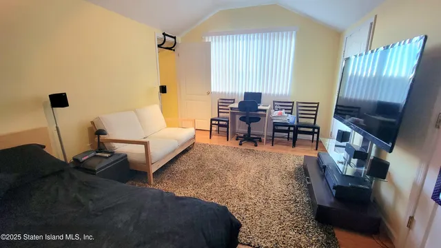 a living room with a bed furniture and a flat screen tv