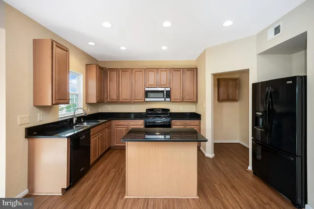 a kitchen with granite countertop a refrigerator stove top oven and sink