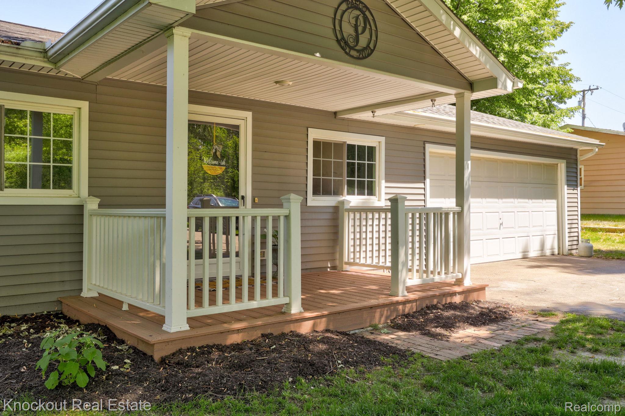 8845 Ormes Road Vassar, MI 48768 - Photo 3 of 35 Covered front porch with wood-finish decking, white railings, and gray siding