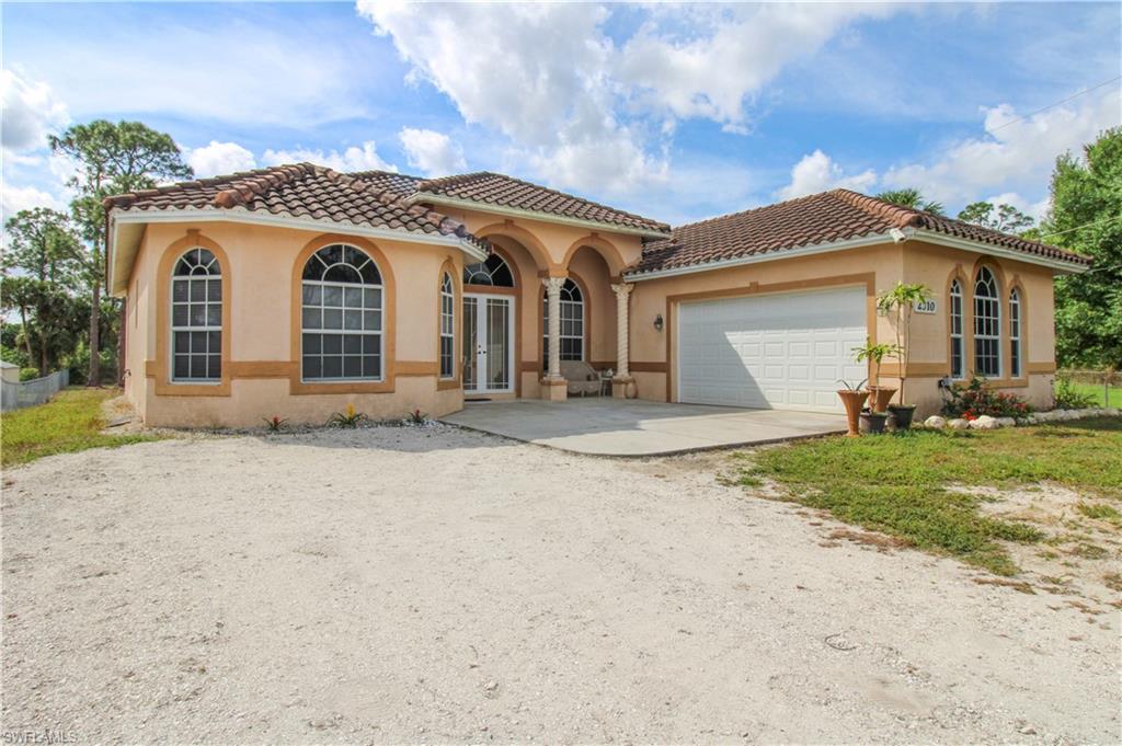 2310 2nd Avenue Southeast Naples, FL 34117 - Photo 2 of 43 a front view of a house with a yard and garage