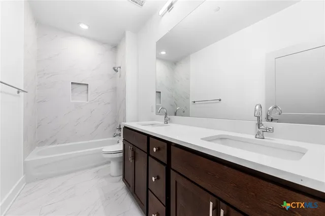 a bathroom with a granite countertop sink a toilet and bathtub