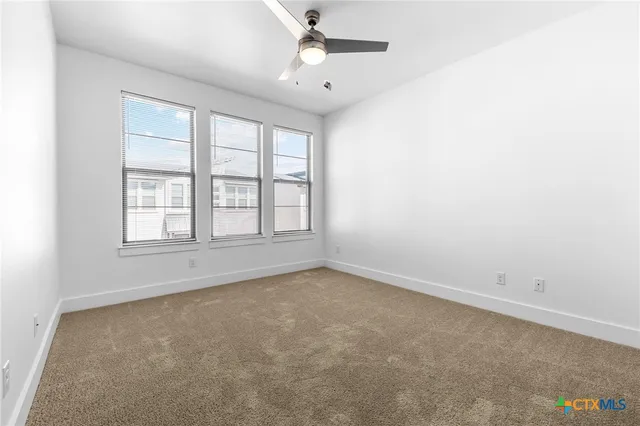 an empty room with a window and a ceiling fan