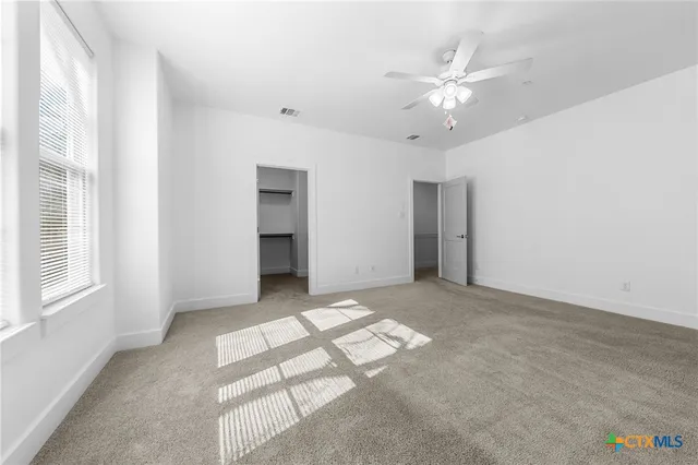 an empty room with windows and ceiling fan