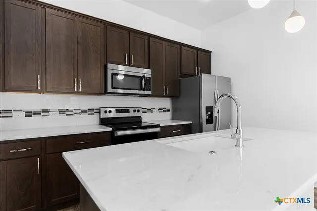 a kitchen with granite countertop a refrigerator stove and microwave with wooden floor