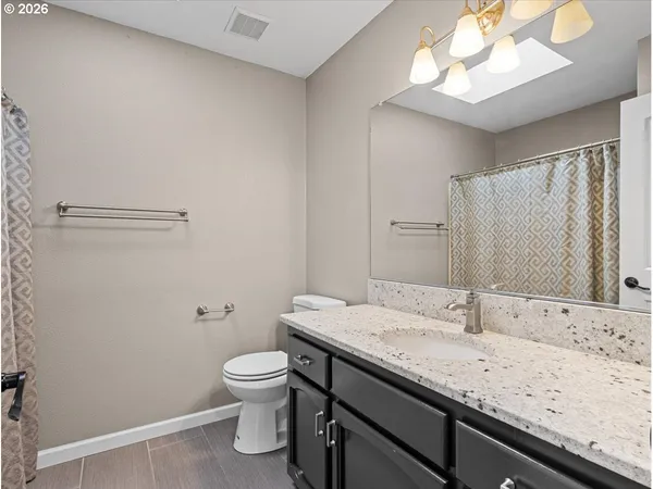 a bathroom with a granite countertop sink a toilet and a mirror