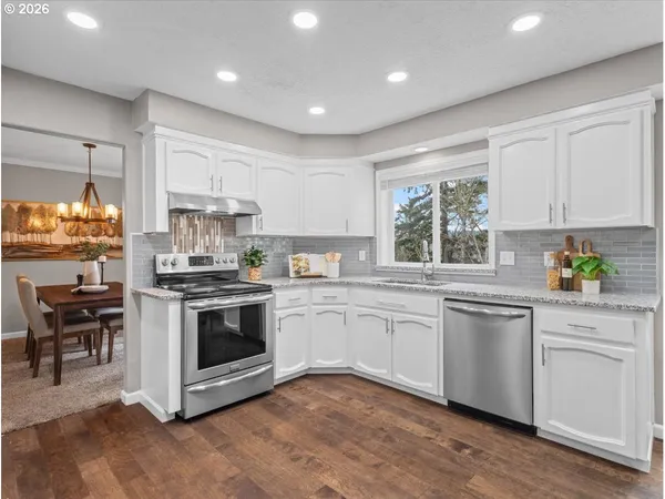 a kitchen with stainless steel appliances granite countertop a stove and white cabinets