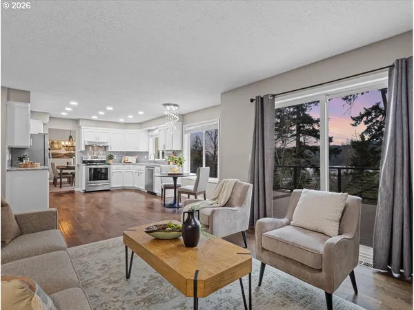a living room with furniture kitchen view and a large window