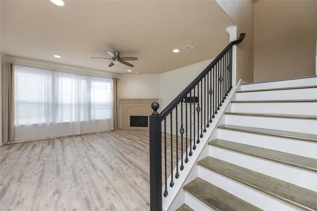 a view of staircase with wooden floor and fan