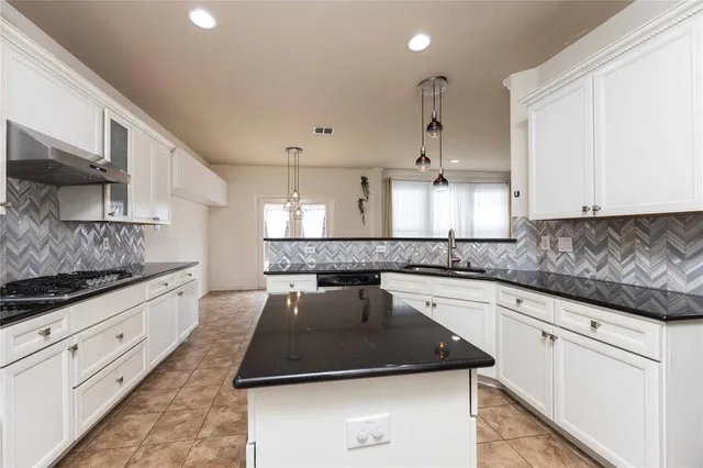 a kitchen with kitchen island granite countertop a sink and white cabinets