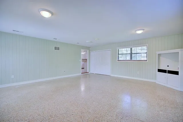 an empty room with windows and chandelier fan