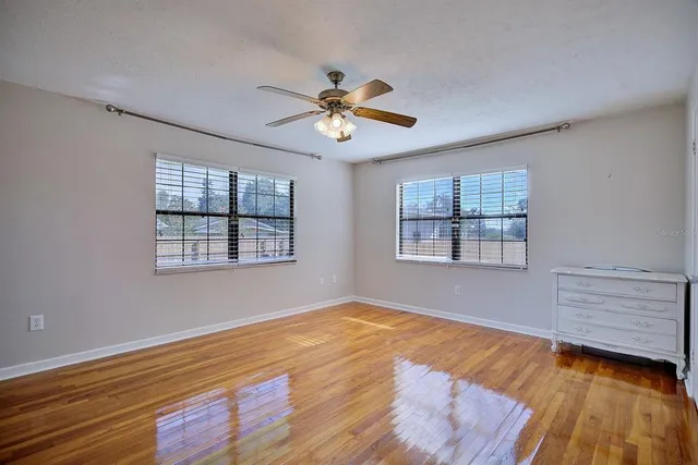 a view of an empty room with window and wooden floor