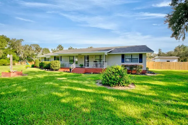 a view of a house with a big yard plants and large trees