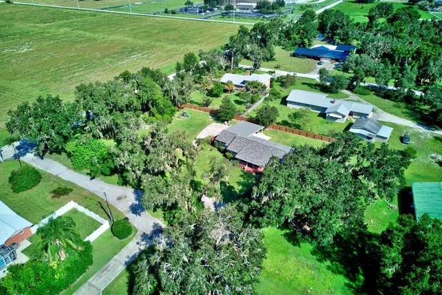 an aerial view of residential house with outdoor space and trees all around