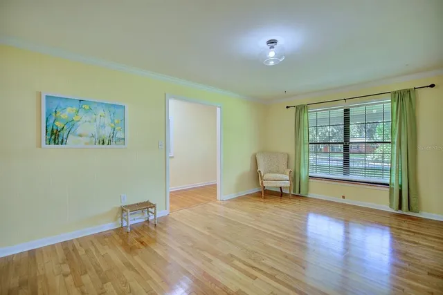 a view of an empty room with a window and wooden floor