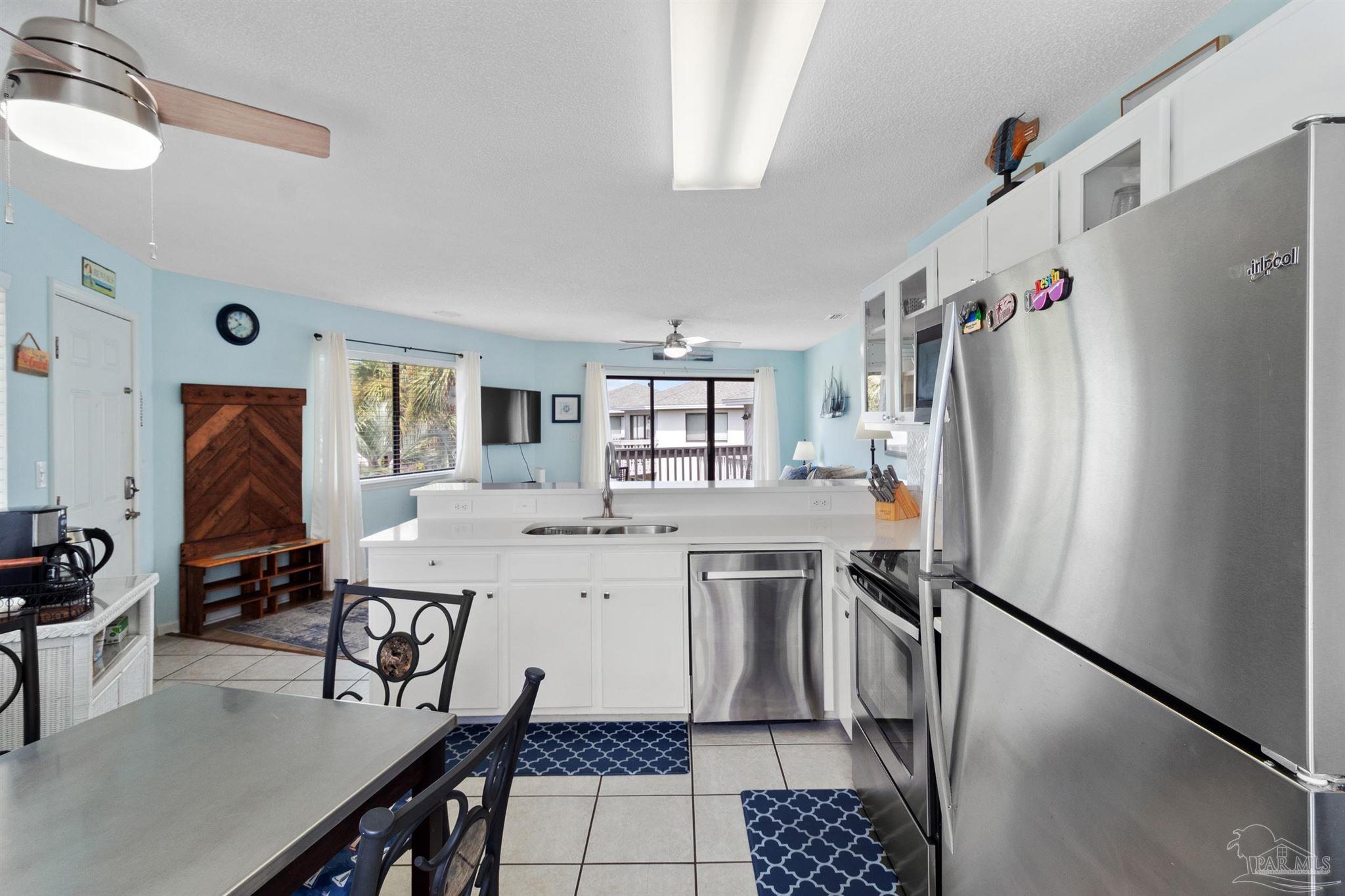 285 Payne Street, Unit 21B Miramar Beach, FL 32550 - Photo 15 of 42 a kitchen with a refrigerator a sink dishwasher a dining table and chairs with wooden floor